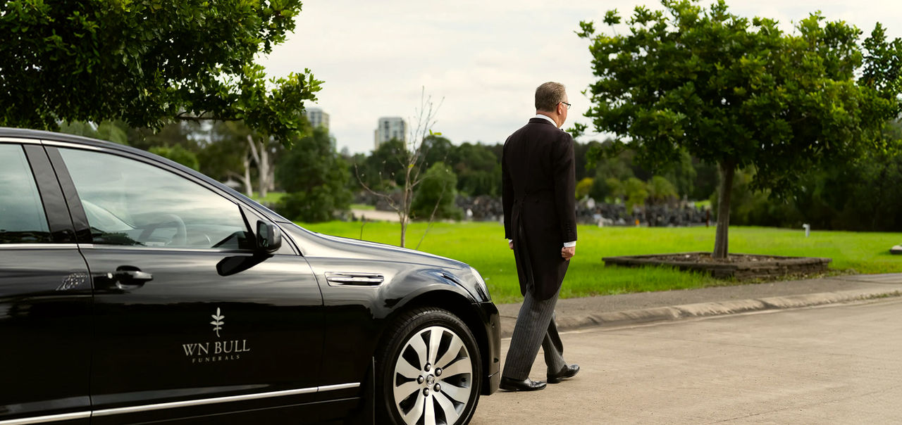 funeral arranger walking ahead of the hearse