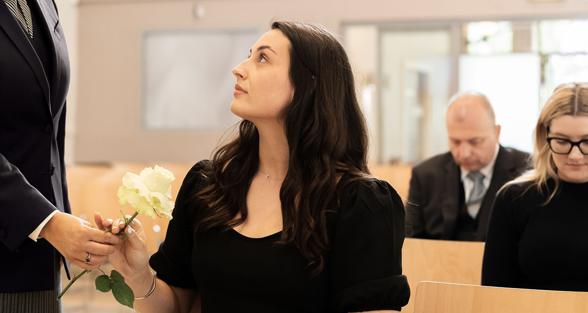 funeral arranger handing woman a flower